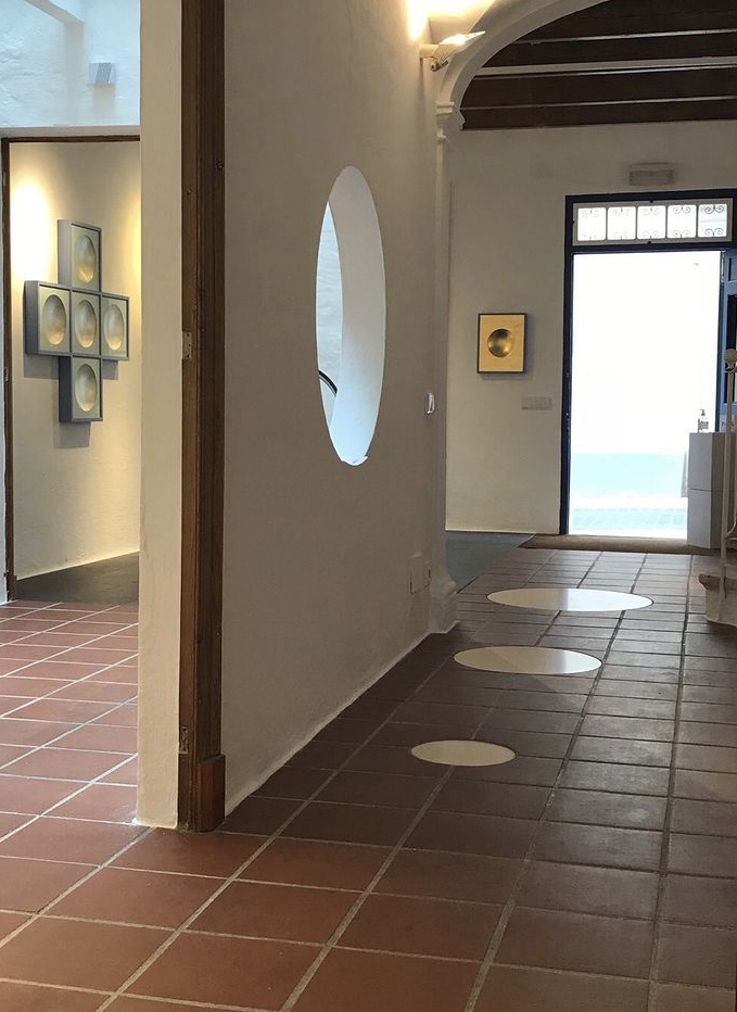 Contemporary art gallery with modern wall art and circular floor designs, featuring minimalist architecture and natural light.